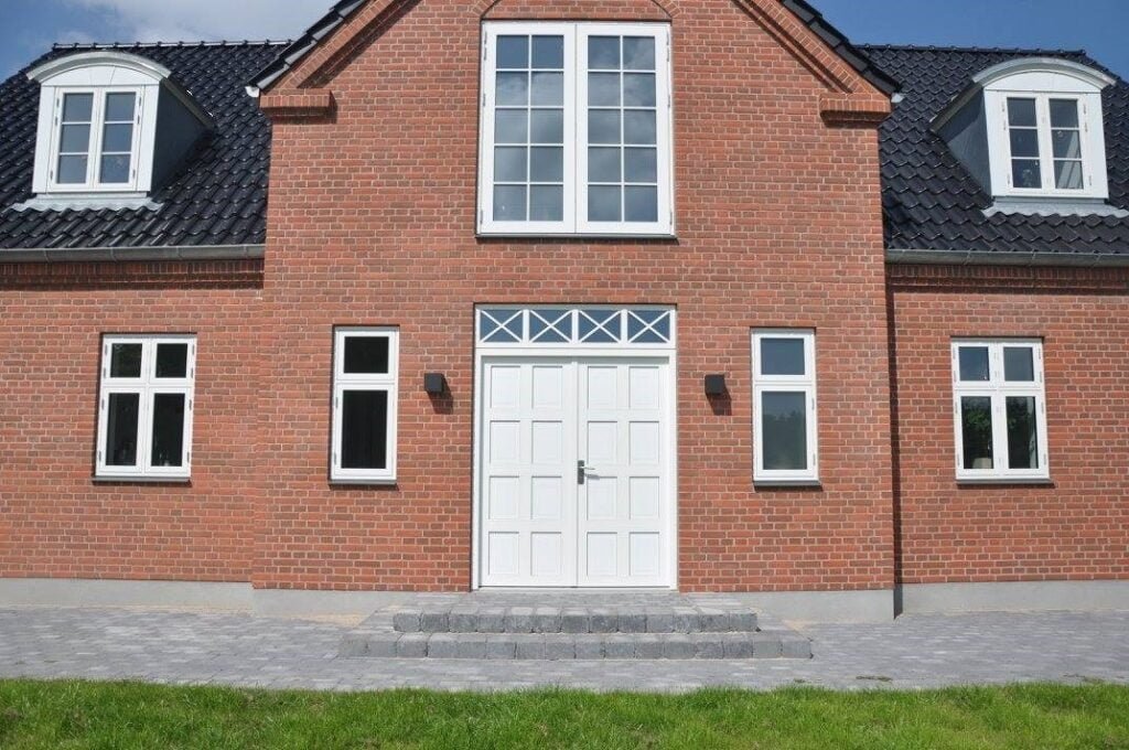 Rødt murstenshus med hvide vinduer og dør