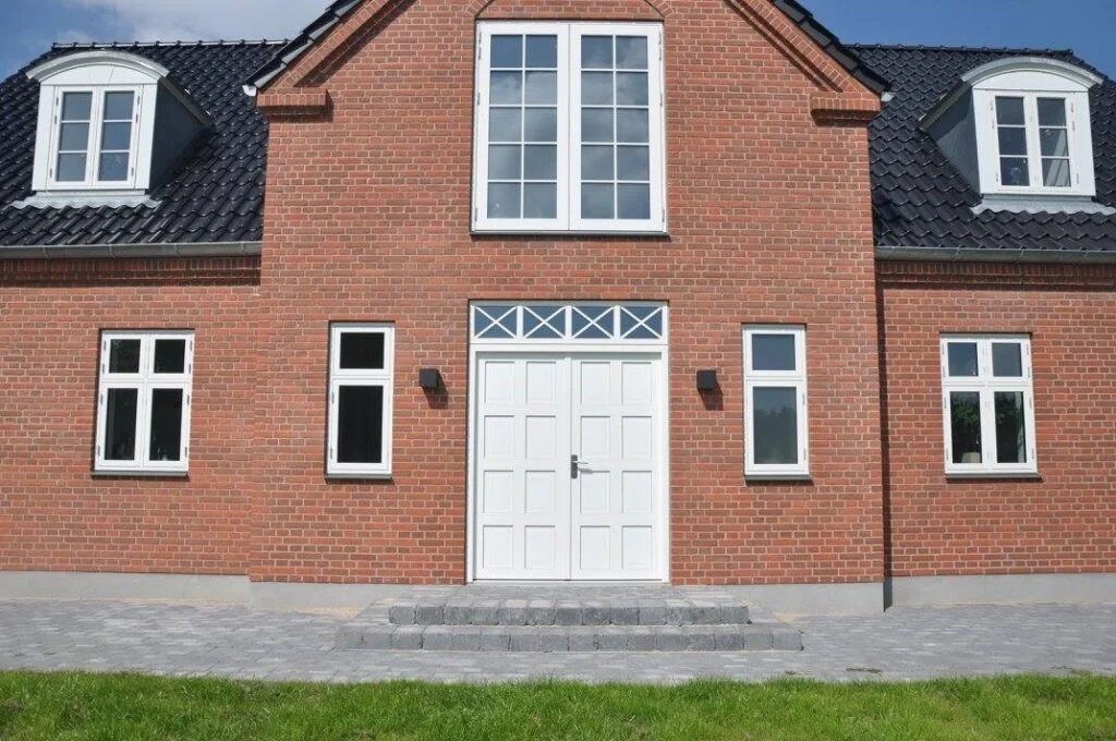 Rødt murstenshus med hvide vinduer og dør