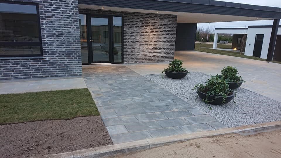Moderne indkørsel med grå belægning og plantekrukker