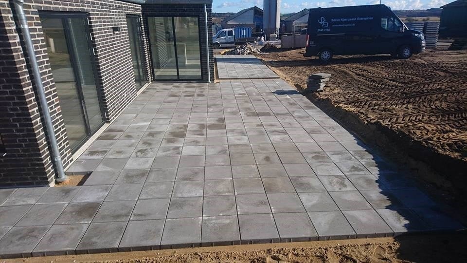 Nybygget terrasse med grå fliser ved murstenshus